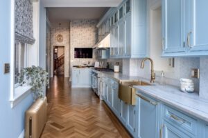 Bright blue cabinets contrast beautifully with rich wood floors in this stylish and contemporary kitchen space designed by Five One Eight Contracting.
