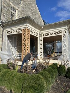 Two men actively working together on a wrap around porch, surrounded by tools and materials, showcasing teamwork in home renovation.