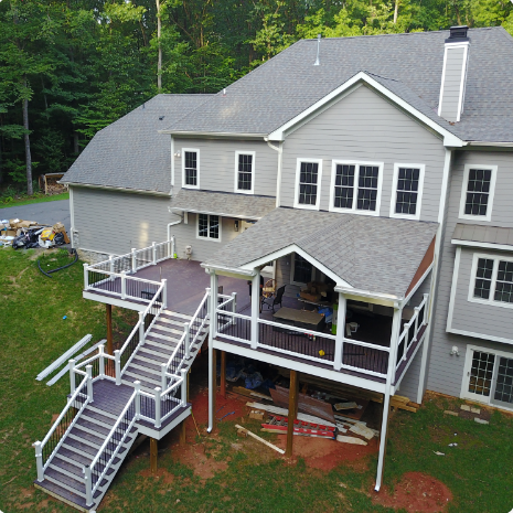 A drone shot of a deck nearing completion on the backside of large home.