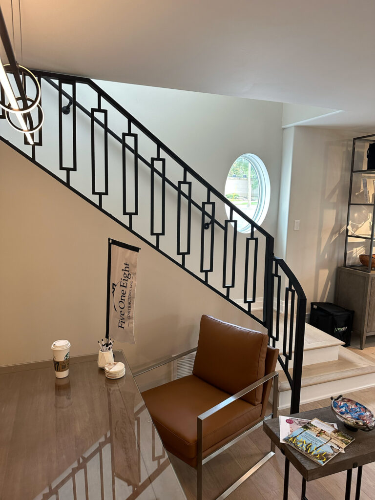 Modern interior with a stylish metal staircase featuring geometric balusters and a circular window to let natural light in.