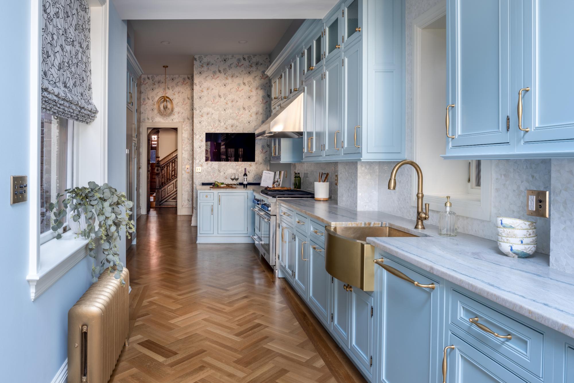 Bright blue cabinets contrast beautifully with rich wood floors in this stylish and contemporary kitchen space designed by Five One Eight Contracting.
