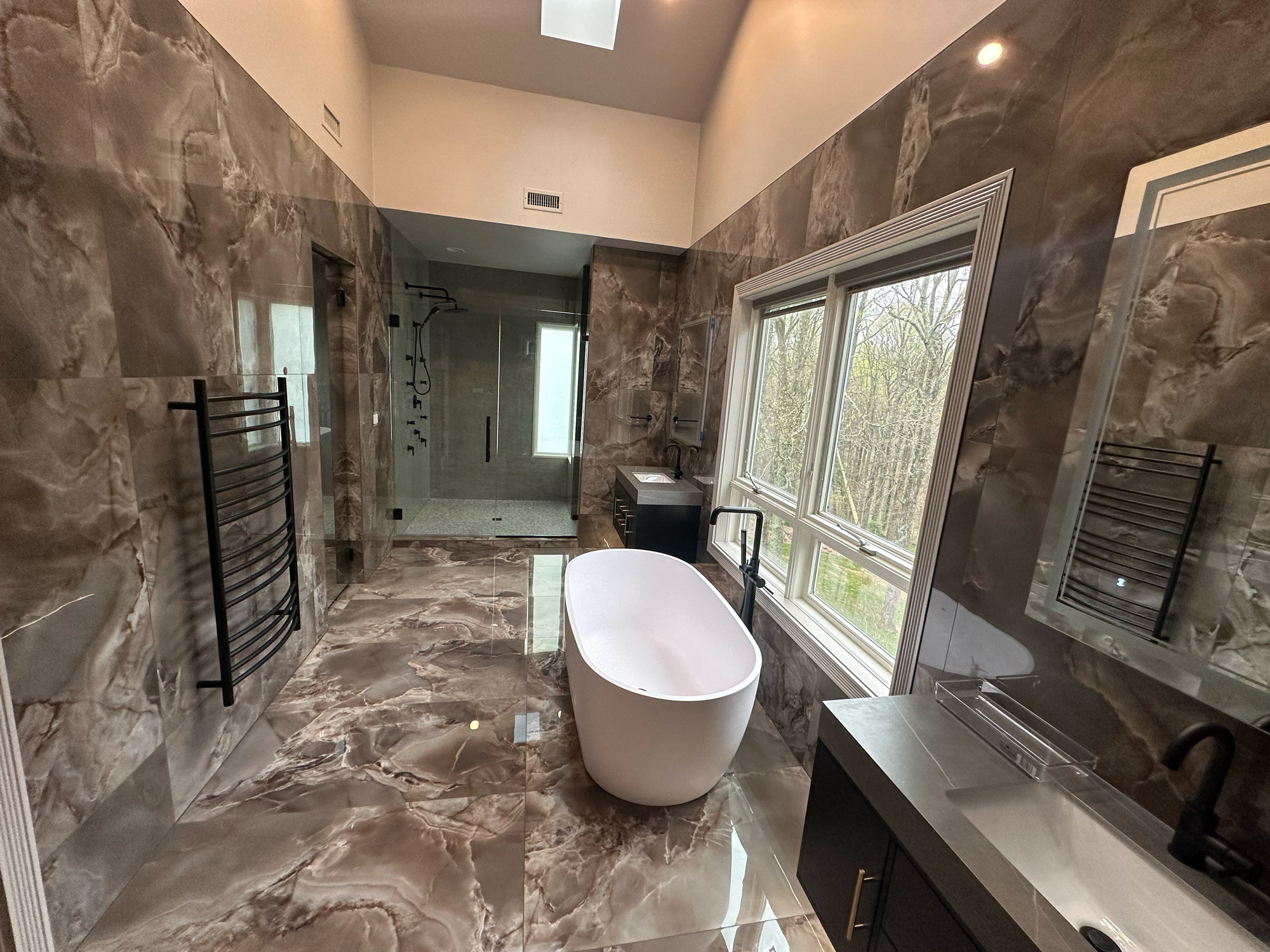 A spacious bathroom featuring elegant marble flooring and a luxurious bathtub, creating a serene and stylish atmosphere.
